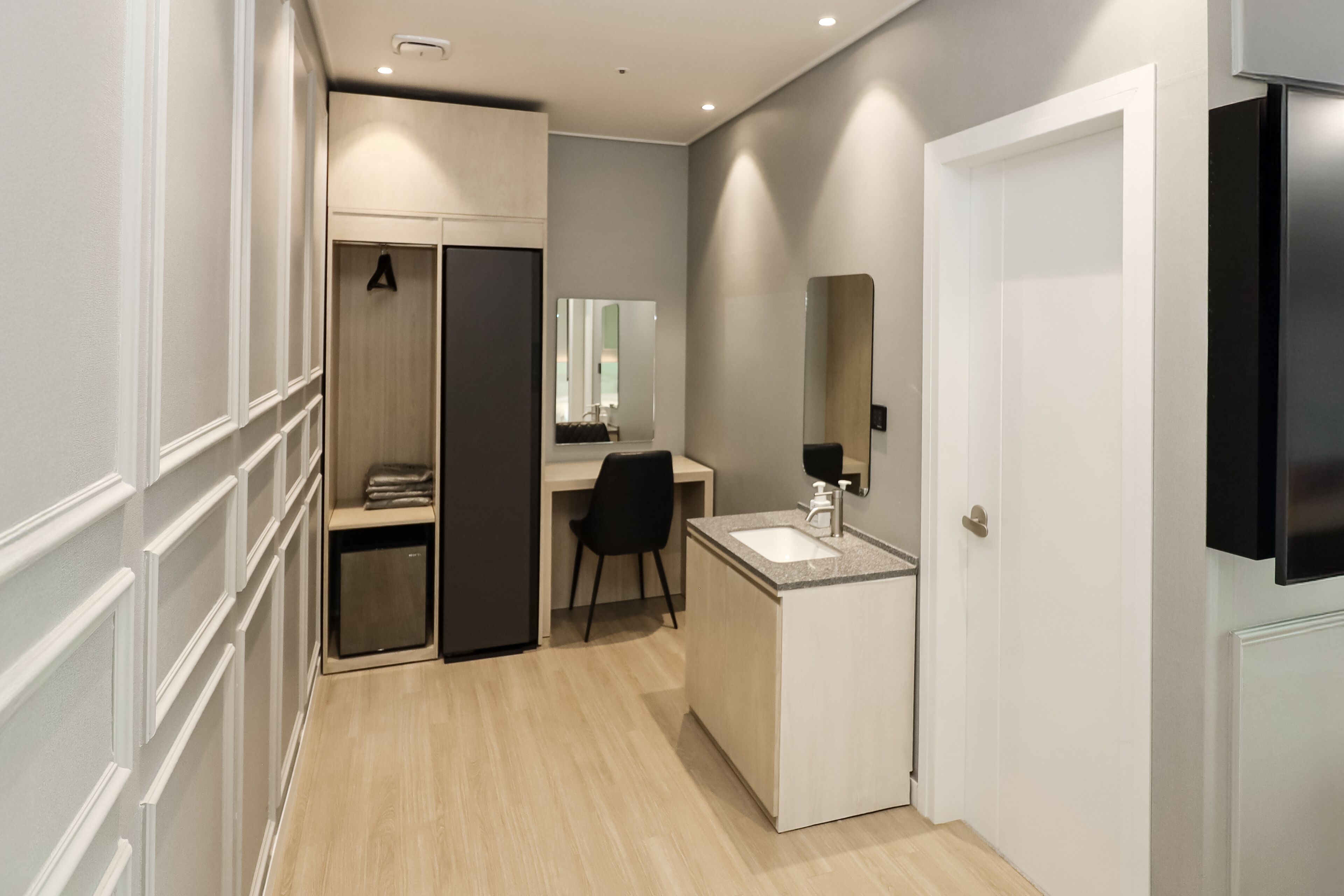 Un baño moderno con tocador, espejo y zona de ducha.