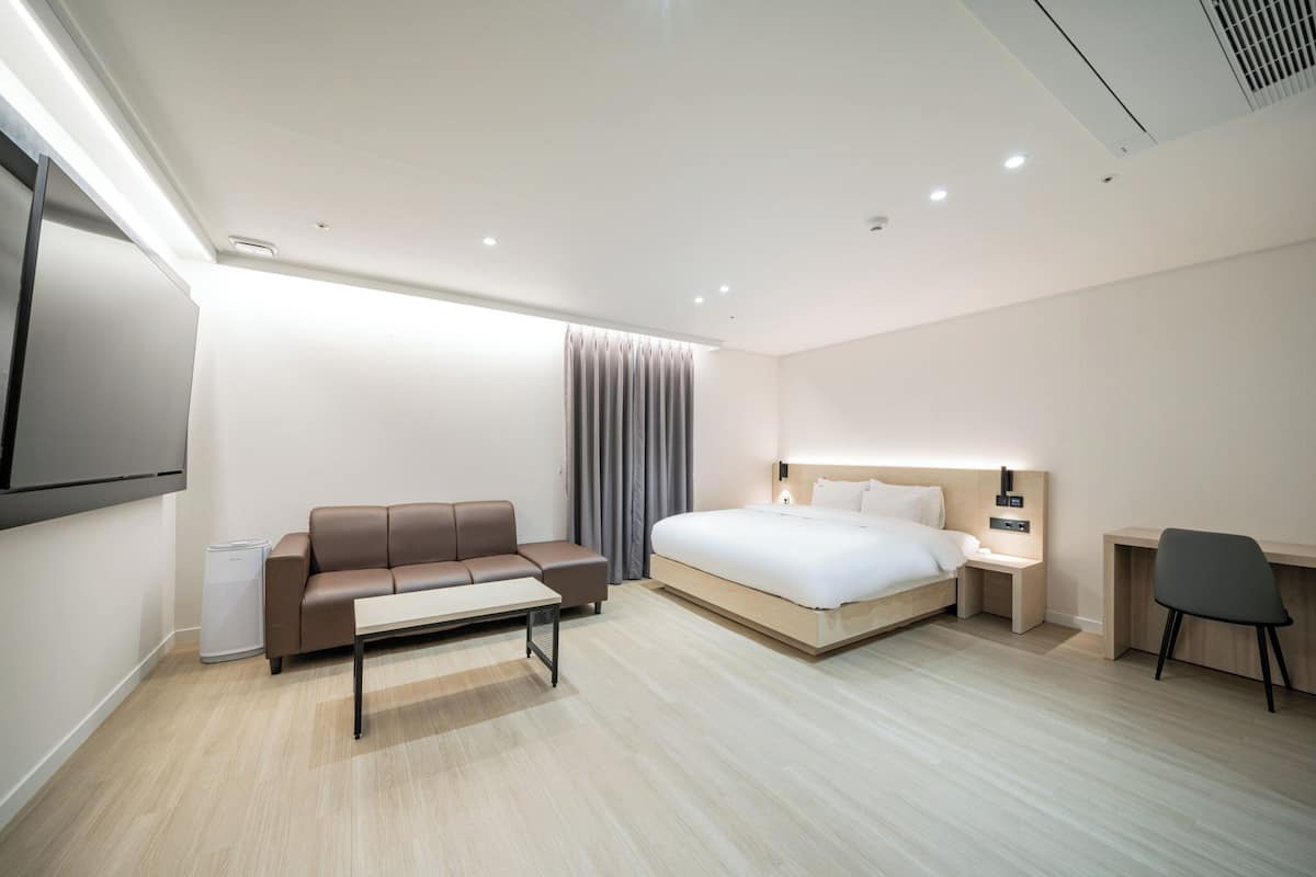 Een moderne hotelkamer met een bed, een sofa, een bureau en een televisie.