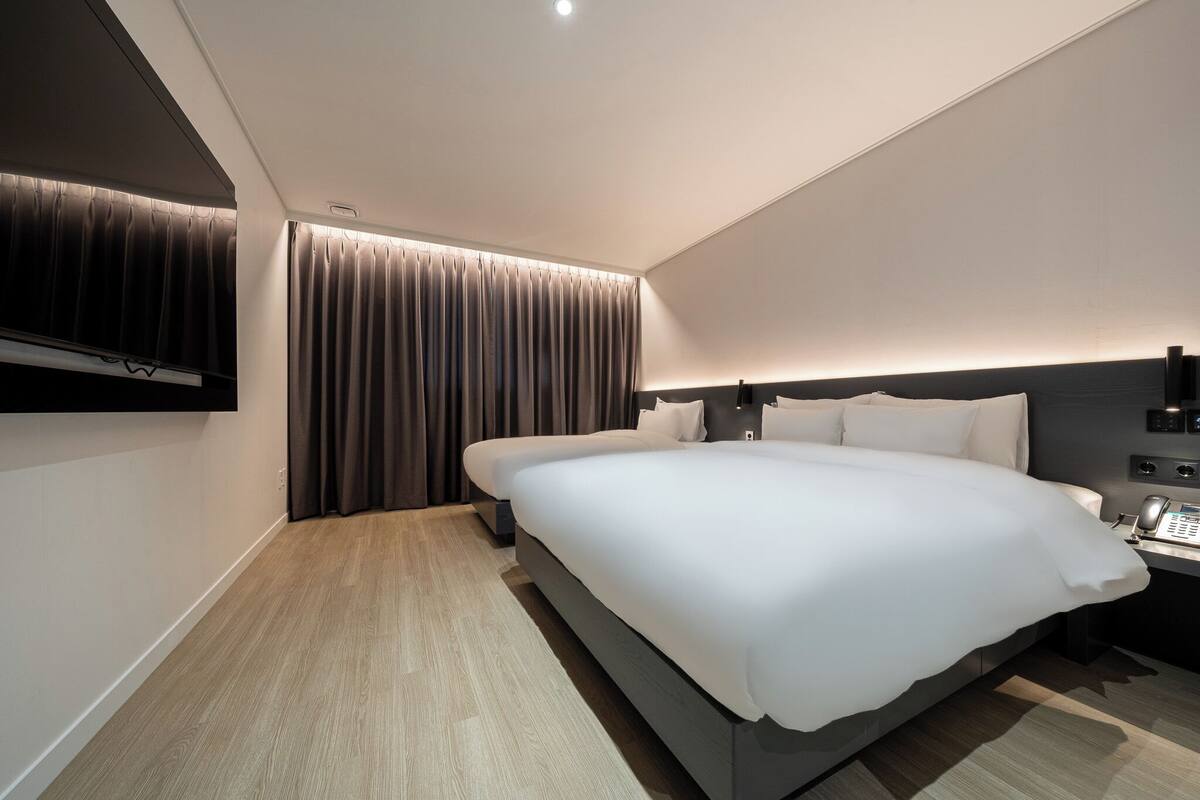 Een moderne hotelkamer met een groot bed, een nachtkastje met telefoon en een wandtelevisie.