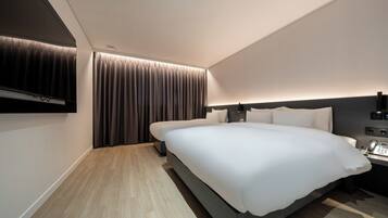 Een moderne hotelkamer met een groot bed, een nachtkastje met telefoon en een wandtelevisie.