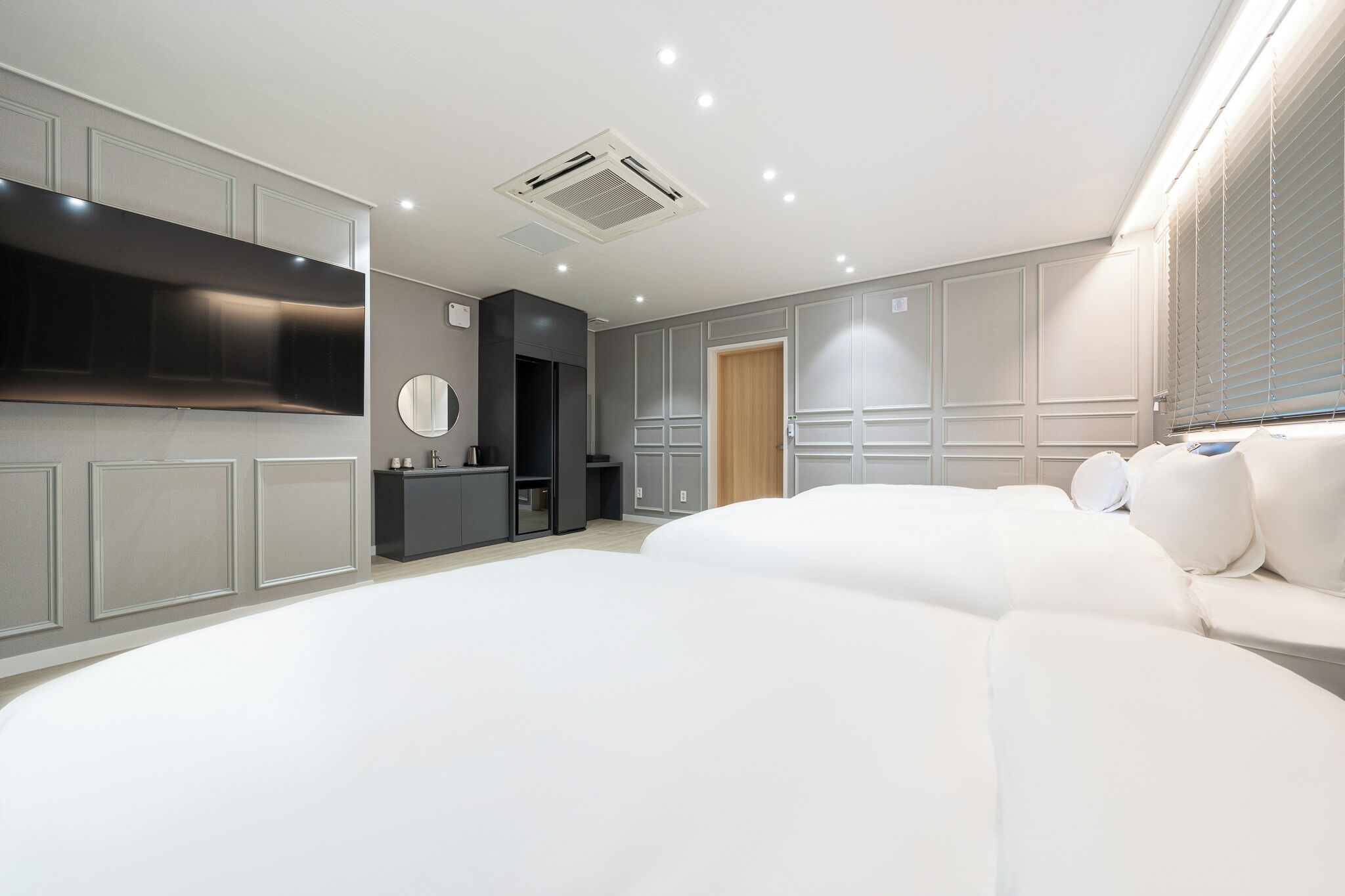 Un dormitorio moderno con una cama grande, un tocador y televisión integrada.