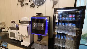 A hotel reception area with a coffee machine, a digital display, and a water dispenser.
