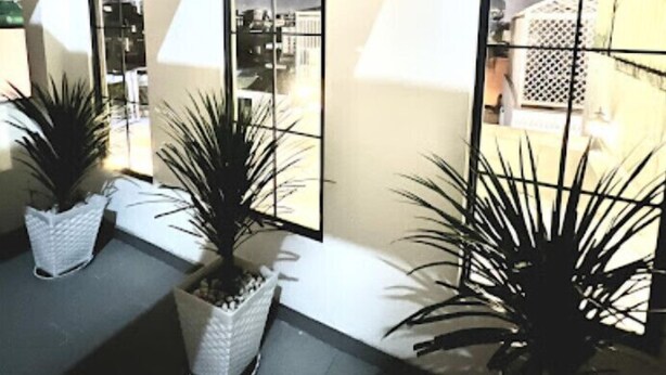 A modern interior with large arched windows, potted plants, and a geometric wall design. - Rose Hotel - by Bay Luxury (Ho Chi Minh City)