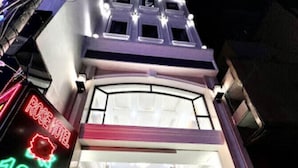 A hotel entrance with a neon sign, a staircase, and a glass door leading to the interior. - Rose Hotel - by Bay Luxury (Ho Chi Minh City)