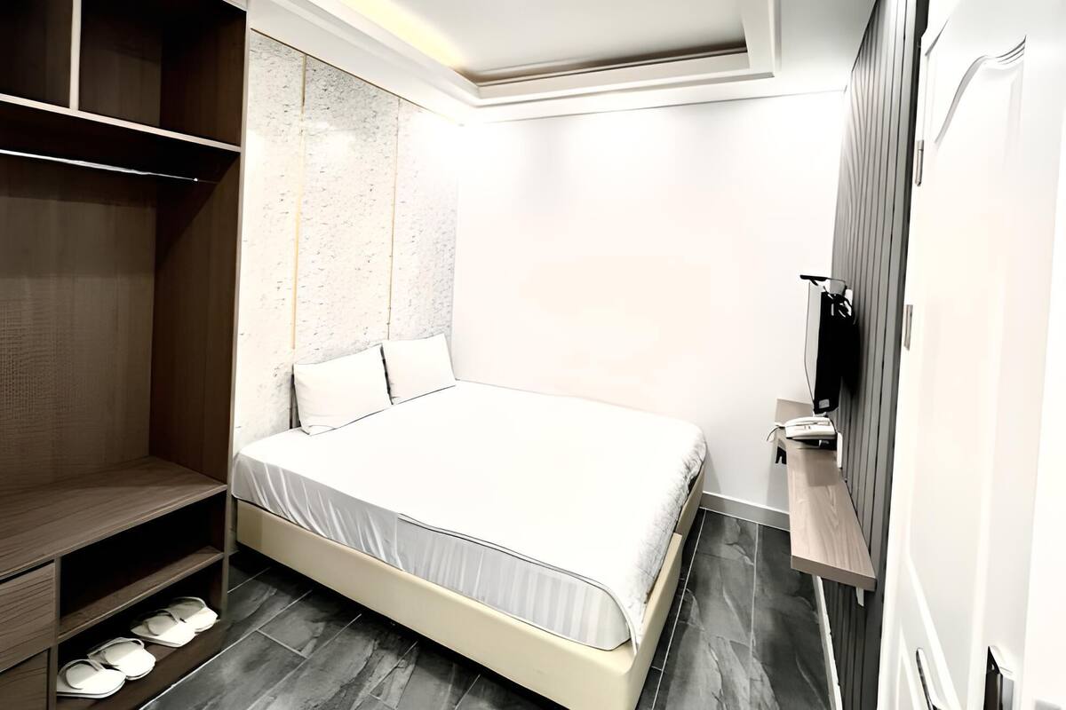 A modern bedroom with a bed, built-in wardrobe, and a small seating area.