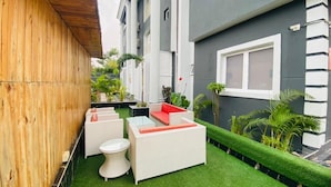 A small outdoor patio with artificial grass, white wicker furniture, and potted plants. - Presken Hotel Ikoyi (Lagos)
