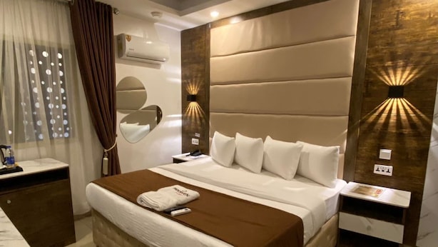 A modern hotel room with a large bed, a marble-tiled floor, and a wall-mounted air conditioner. - Presken Hotel Ikoyi (Lagos)