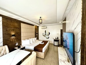 A hotel room with a bed, a sofa, a TV, a minibar, and a mirror. - Presken Hotel Ikoyi (Lagos)