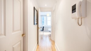 A hallway with a white door, a framed picture on the wall, and a wall-mounted telephone. - 1BR with Balcony in the Heart of Holborn (London)