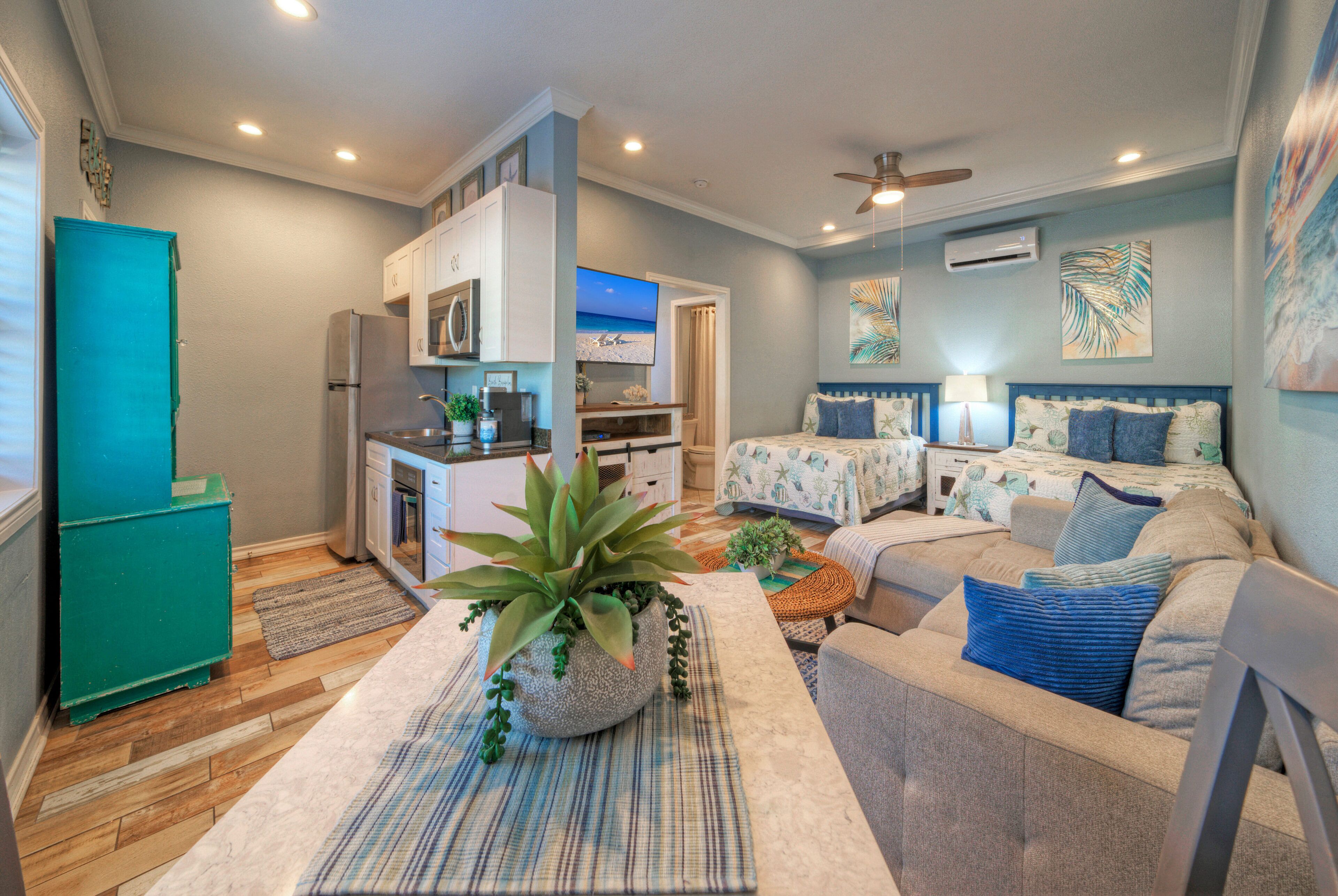 A compact living space with a kitchenette, a dining area, and a bedroom with a bed and two nightstands.