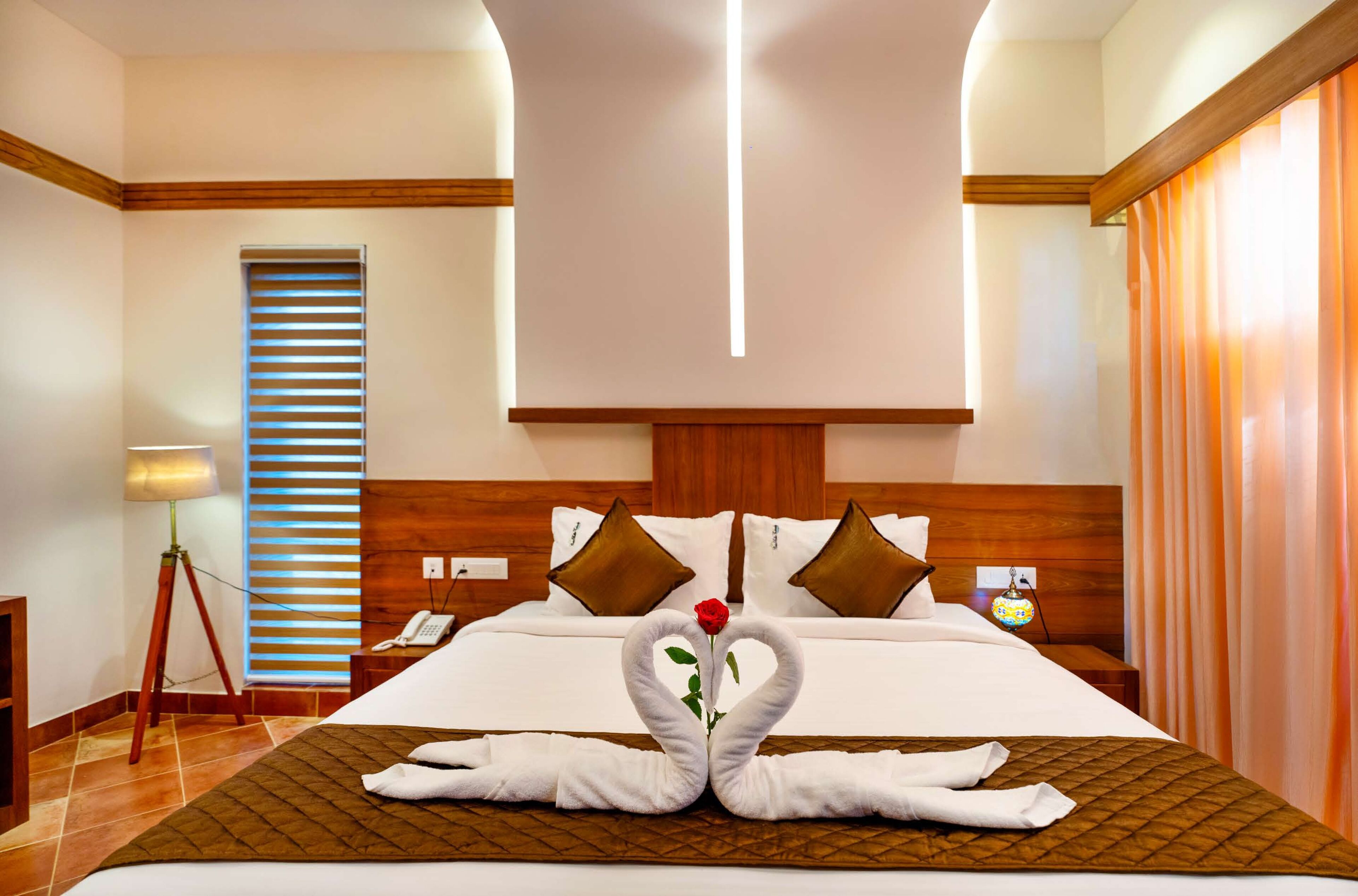 Ein Hotelzimmer mit einem großen Bett, einem hölzernen Kopfteil und einer dekorativen Handtuchgestaltung auf dem Bett.
