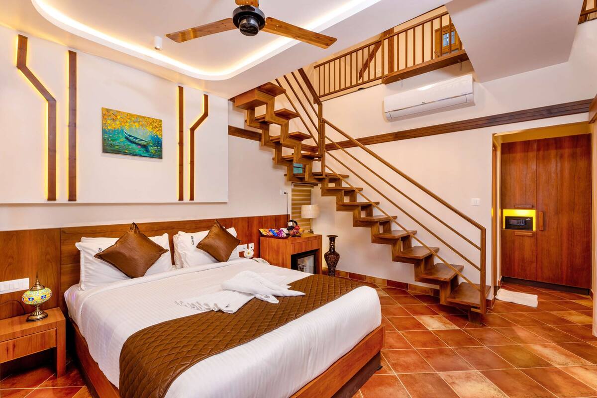A hotel room with a large bed, wooden staircase, and a painting on the wall.