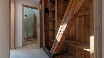 A room with a wooden staircase, a glass door leading to a bathroom, and a carpeted floor.
