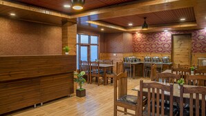 Un restaurante con paredes y techo de madera, mesas y sillas de madera, y un ventanal.