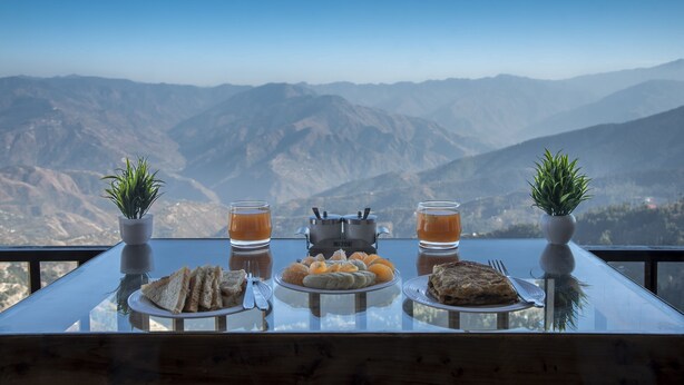 Una mesa con comida y bebidas, con vistas a un paisaje montañoso.