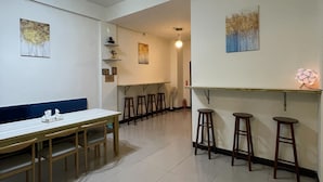 A spacious room with a dining table, multiple stools, and a ceiling fan. - Yilan (Jincheng)