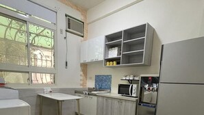 A modern kitchen with white cabinets, a built-in microwave, a refrigerator, and a window with decorative iron bars. - Yilan (Jincheng)