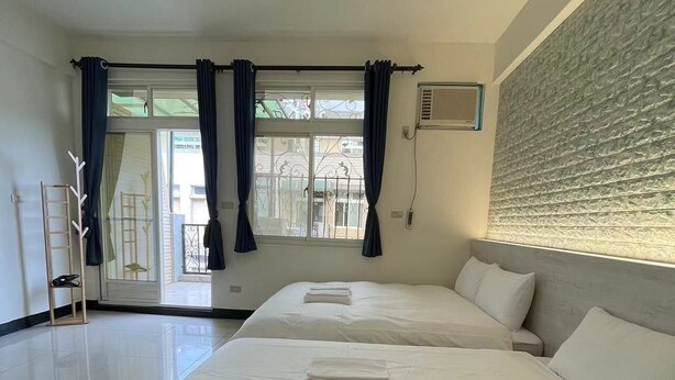 A hotel room with two beds, a large window with curtains, a balcony, and a textured wall. - Yilan (Jincheng)