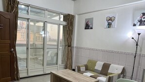 A spacious living room with a wooden coffee table, a sofa, and a light-colored armchair. A sliding glass door leads to an outdoor area. - Yilan (Jincheng)