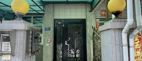 Une entrée abritée, dotée d’un portail en métal, d’un sol carrelé et d’un toit végétalisé.