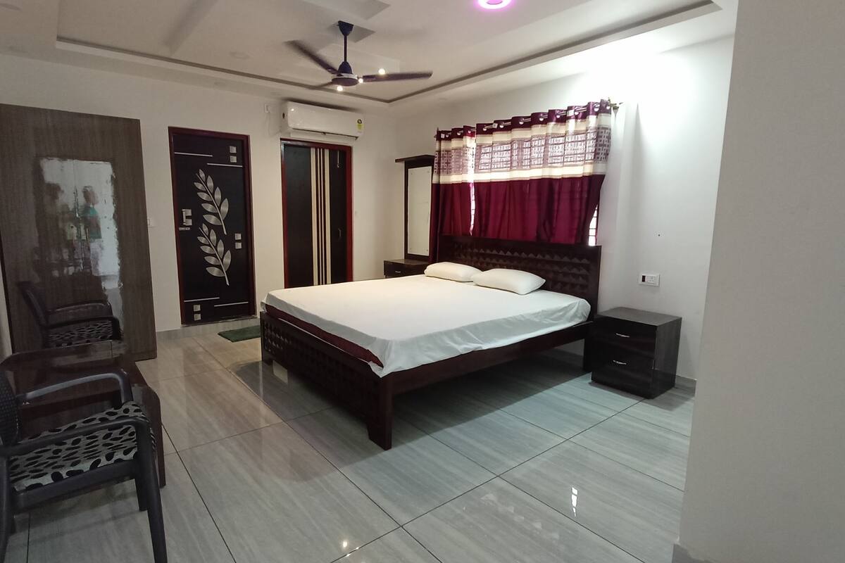 A bedroom with a bed, a chair, a wardrobe, and a ceiling fan.