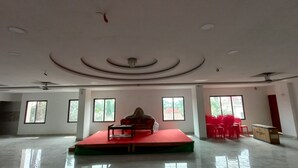 A spacious room with a stage, chairs, and a ceiling fan.