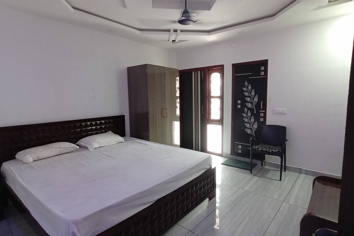 A bedroom with a bed, a chair, a wardrobe, and a door.