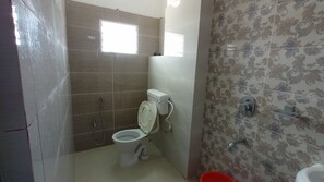 A small bathroom with a toilet, a shower, and a sink.