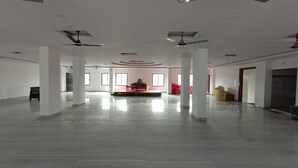 A spacious, well-lit room with a central stage, multiple ceiling fans, and a polished floor.