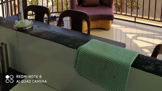 A balcony with a sofa and chairs, a table with a candle, and a view of a cityscape. -  Grace Guesthouse (Antananarivo)