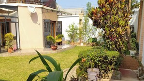 A house with a balcony, potted plants, and a garden area. -  Grace Guesthouse (Antananarivo)