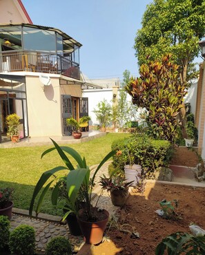 A house with a balcony, potted plants, and a garden area. -  Grace Guesthouse (Antananarivo)