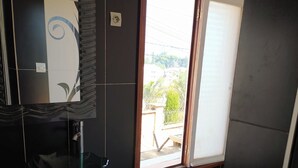 A bathroom with a glass sink, a mirror, and a window with a view of the outside. -  Grace Guesthouse (Antananarivo)