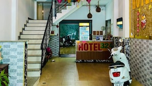 A hotel lobby with a reception desk, a staircase, and a scooter parked near the desk.
