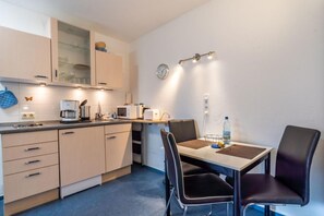 A compact kitchen with modern appliances, a dining area with two chairs, and a small table.