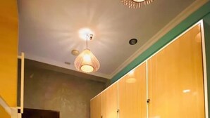 A hallway with a wooden wardrobe, a hanging light fixture, and a door. - Fomo hostel palawan (Puerto Princesa)