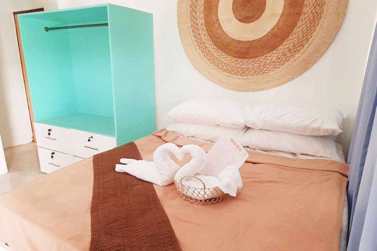 A bedroom with a bed, a blue wardrobe, and a wall-mounted circular decoration.
