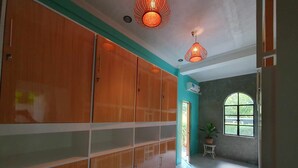 A hallway with wooden lockers, a tiled floor, and a window with a view of greenery. - Fomo hostel palawan (Puerto Princesa)