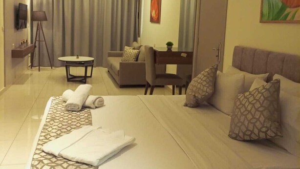 Habitació d'hotel amb un llit gran, una taula de treball, un sofà i una televisió.