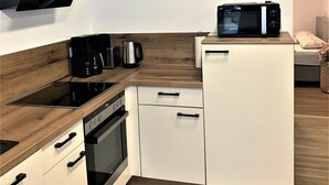 Une cuisine compacte équipée d’un téléviseur à écran plat, d’un four à micro-ondes, d’une machine à café et d’une cuisinière.