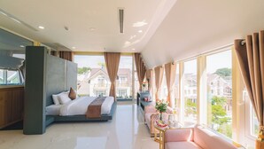 A modern hotel room with a bed, sofa, and dining area. - Quy Tai Premium Hotel (Xuan Huong - Da Lat)