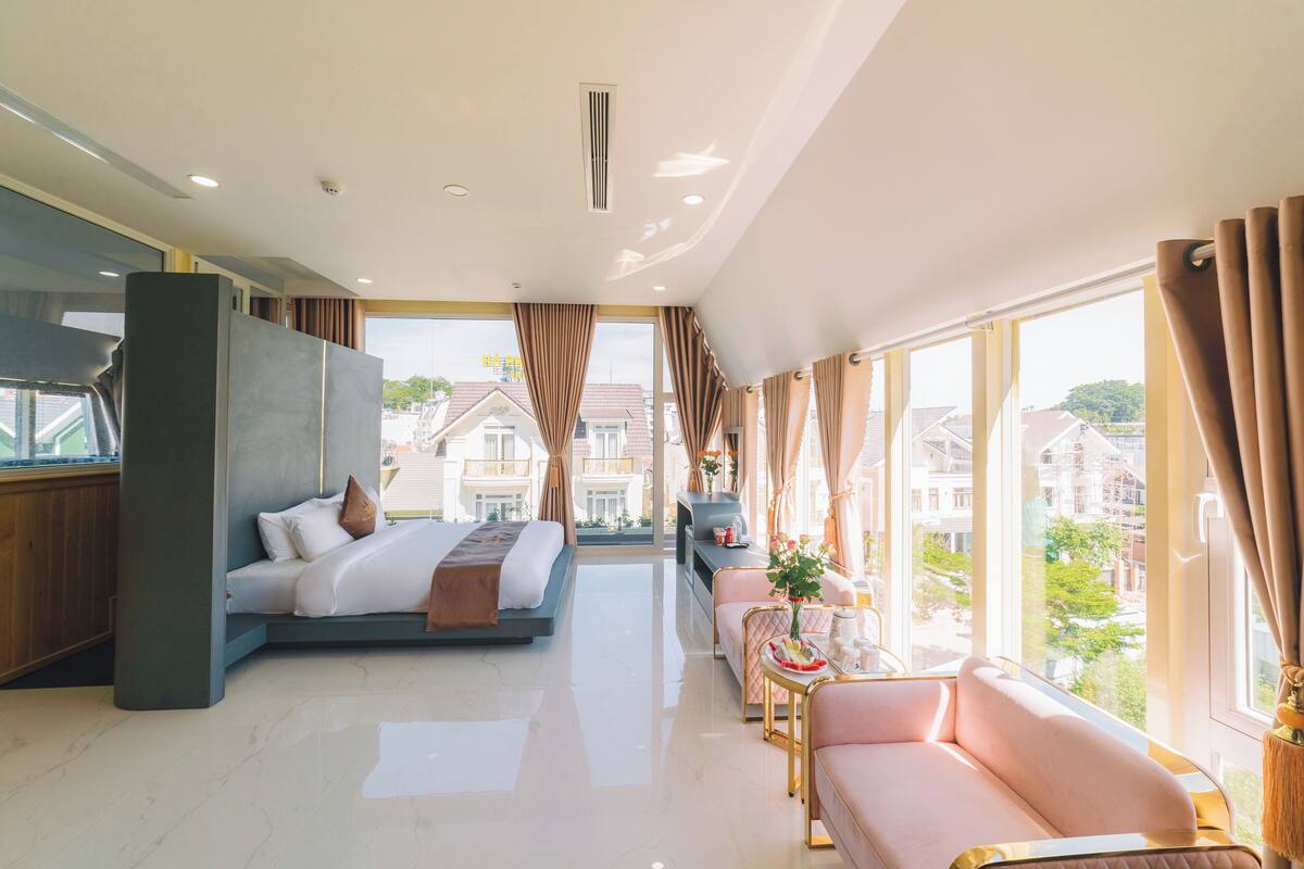 Una habitación de hotel moderna con cama, sofá y zona de comedor.