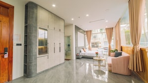 A modern hotel room with a large wardrobe, a sofa, a small table, and a view of the street. - Quy Tai Premium Hotel (Xuan Huong - Da Lat)