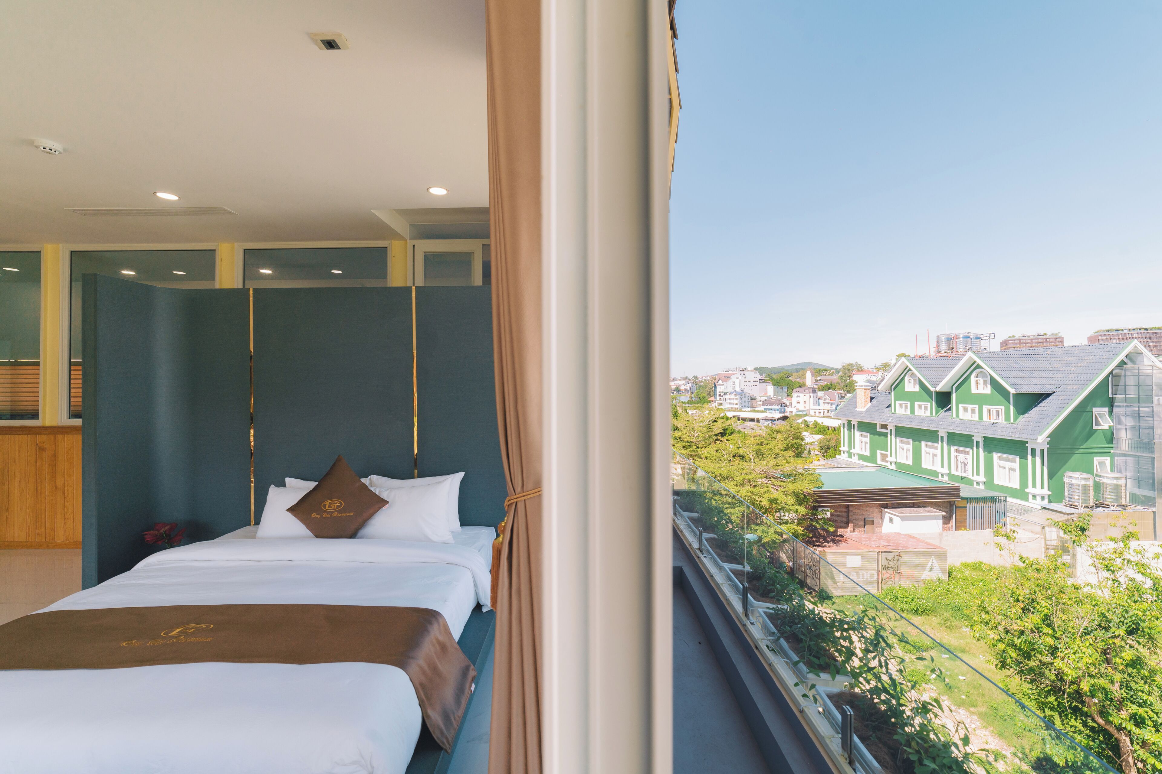 A hotel room with a large bed, a view of the city, and a balcony.