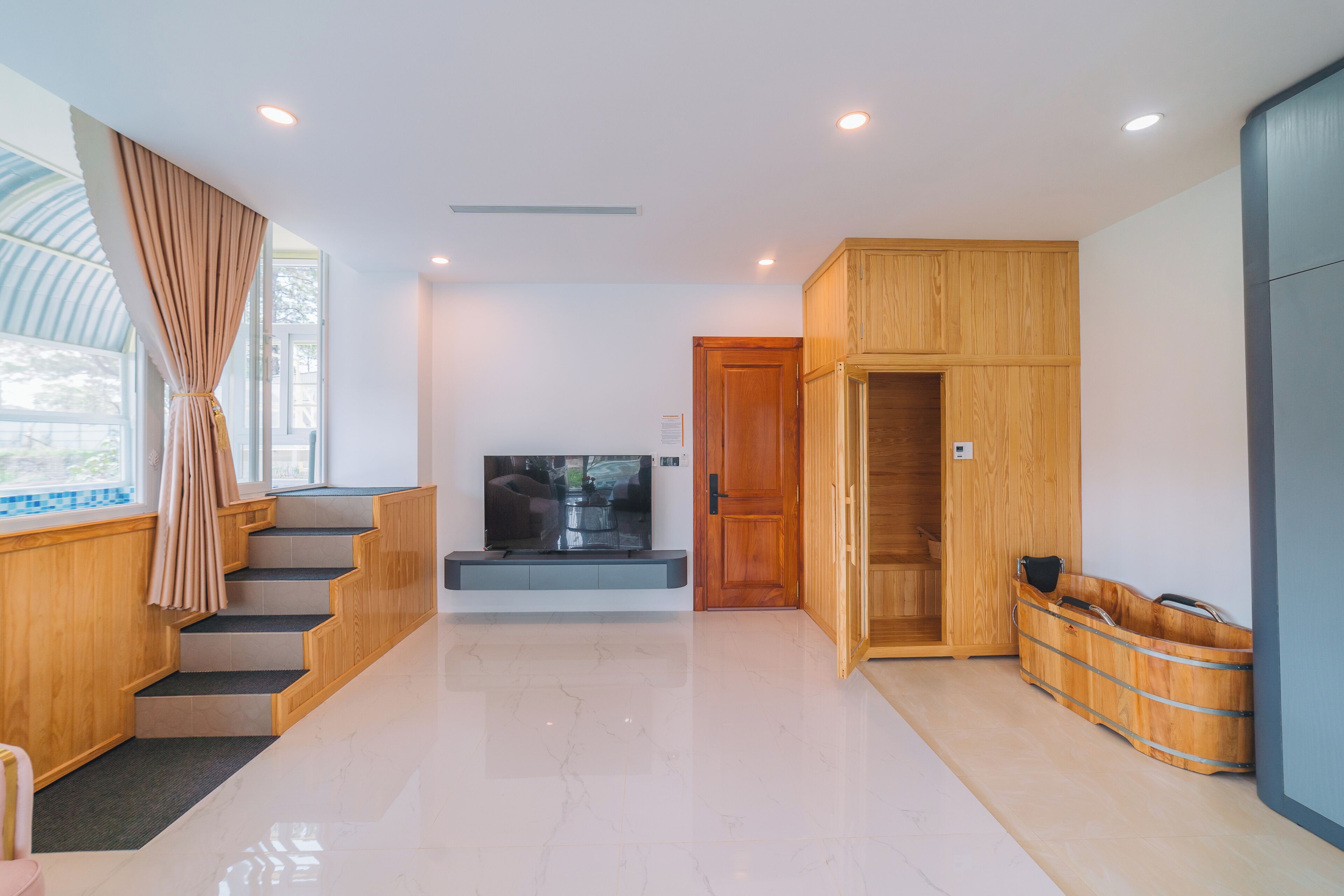 Un interno moderno con una scala, una televisione a schermo piatto, mobili in legno e una sauna.