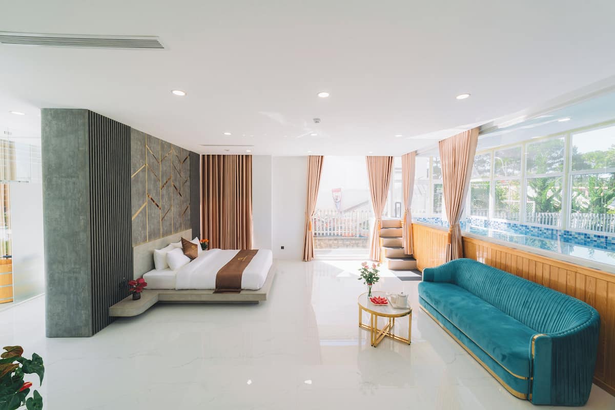 Una habitación de hotel moderna con una cama grande, un sofá, una mesita y vistas a un balcón.