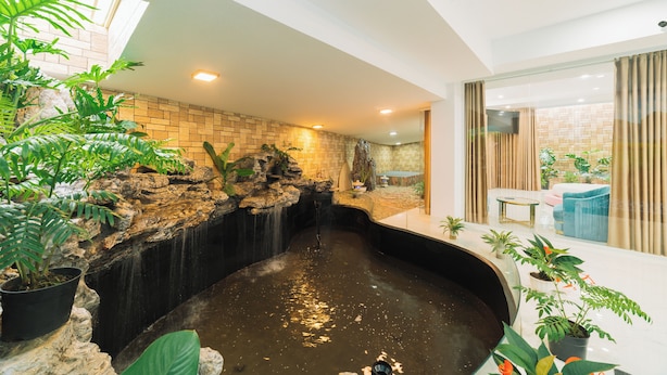 A modern indoor space with a water feature, brick walls, and potted plants. - Quy Tai Premium Hotel (Xuan Huong - Da Lat)