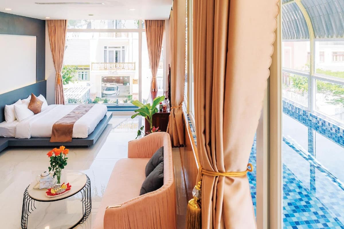 Una habitación de hotel moderna con cama, sofá y una pequeña mesa con un florero.