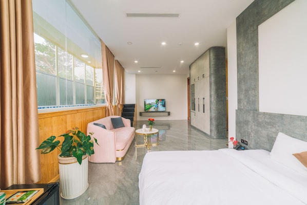 A hotel room with a bed, a sofa, a TV, and a potted plant. - Quy Tai Premium Hotel (Xuan Huong - Da Lat)