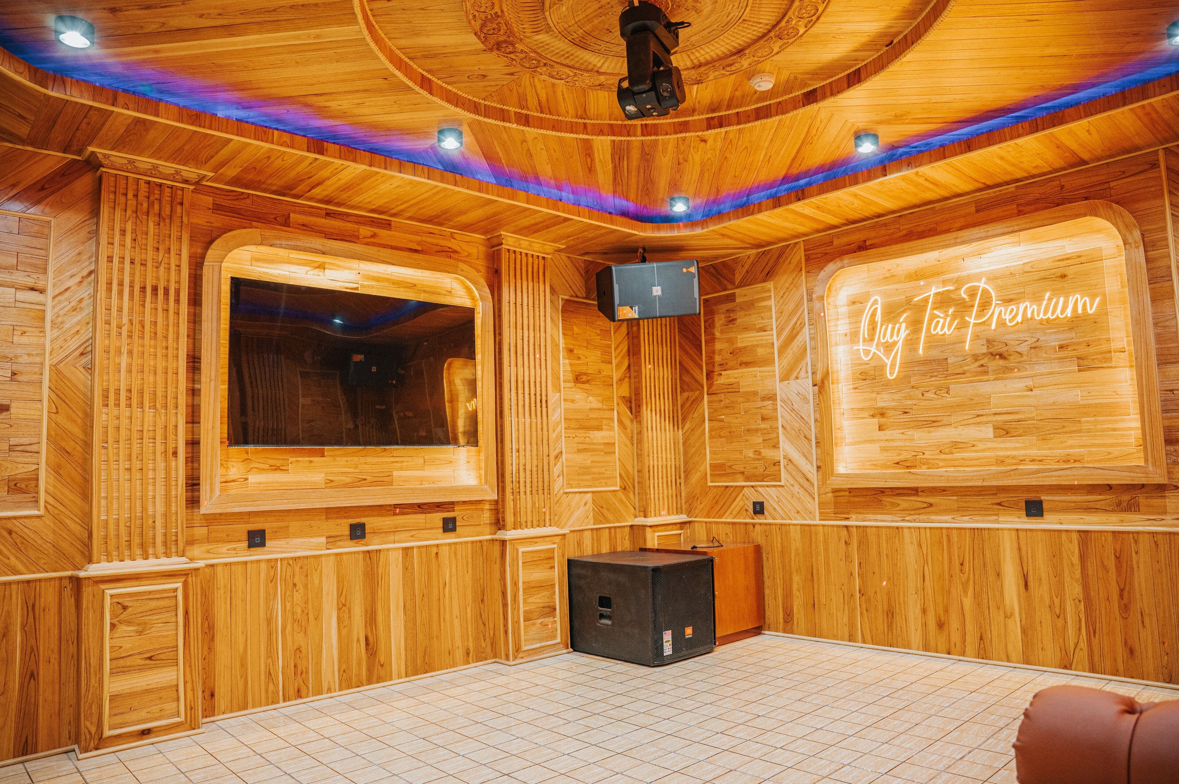 A wooden interior with a large window, a television, and a neon sign reading "Quij Tai Premium".